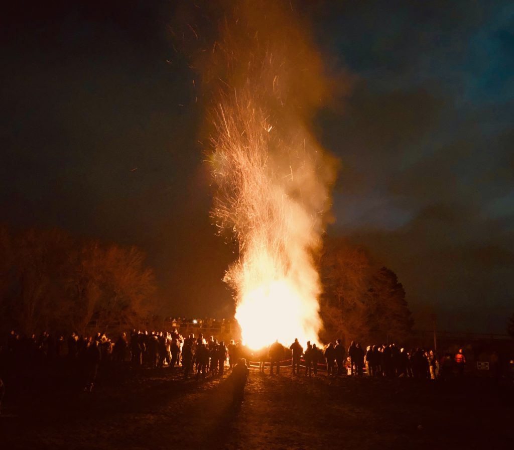 a bonfire plume from winterfest 2020 is bright against a dark night background